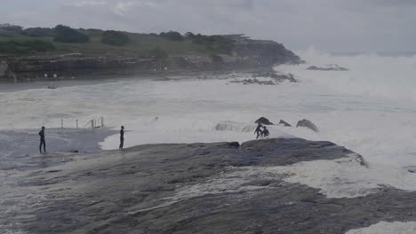 friends having fun with waves during a storm - clovelly beach sydney australia