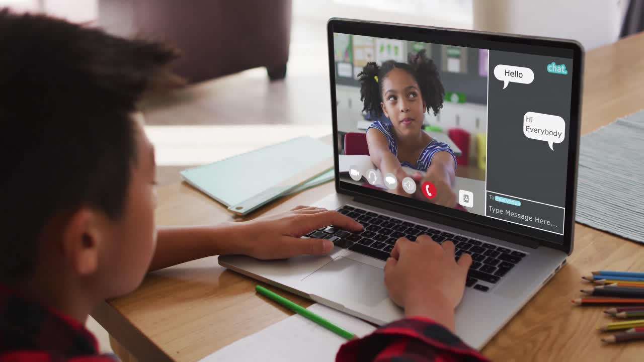 Schoolboy using laptop for online lesson at home, with his colleague and web chat on screen