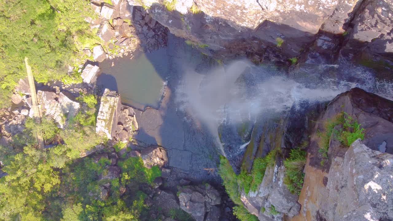 cascada de agua que fluye en un cañón rocoso rodeado de vegetación verde exuberante, vista aérea