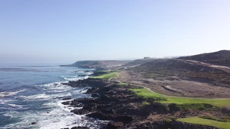 Die-Drohne-Fliegt-Von-Links-Nach-Rechts-Und-Bietet-Einen-Weiten-Blick-Auf-Einen-Golfplatz-Am-Strand-Und-Die-Wüstenlandschaft-Von-Baja