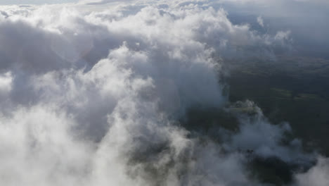 High-aerial-view-over-clouds-moving-over-the-landscape-of-Maui,-Hawaii-on-a-sunny-day