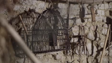 vintage birds cage against wall of stones and other old tools