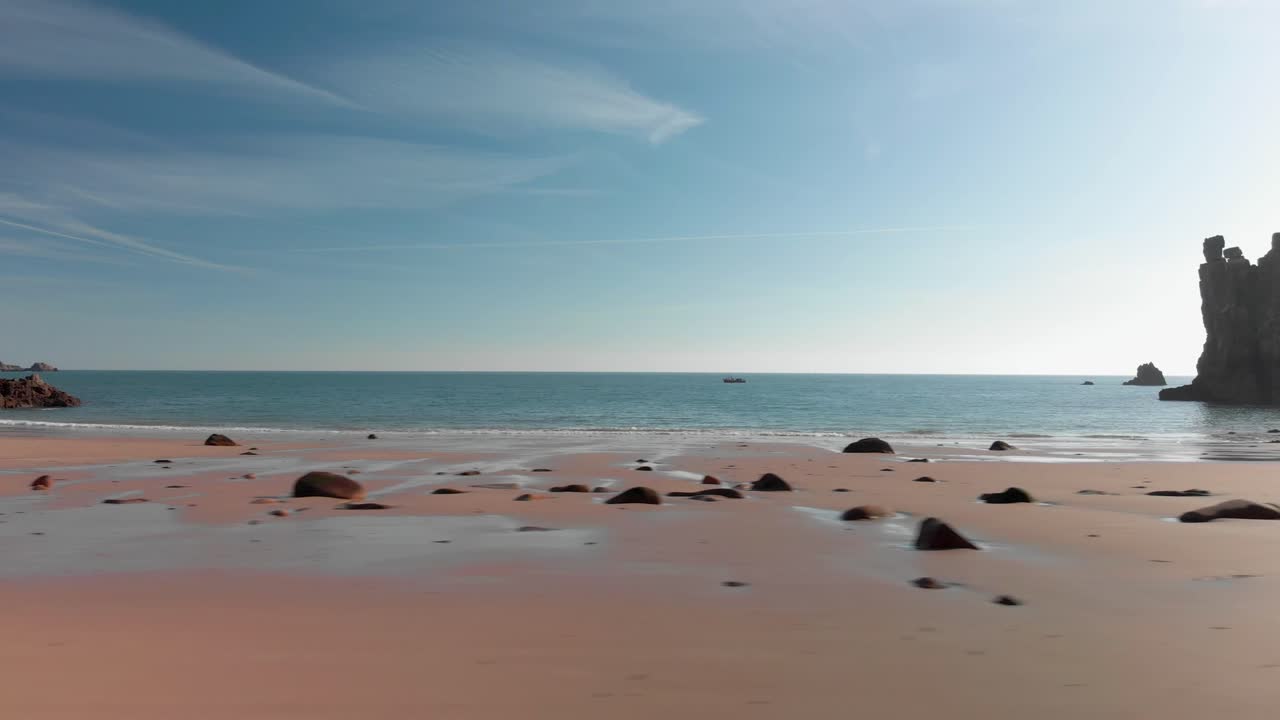 toma aérea sobre una playa de arena con rocas, moviéndose de derecha a izquierda
