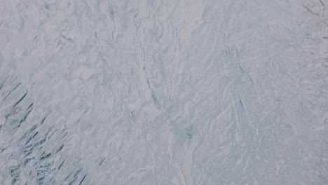 aerial top view over ice cracks and formations in virkisjokull glacier covered in snow, iceland