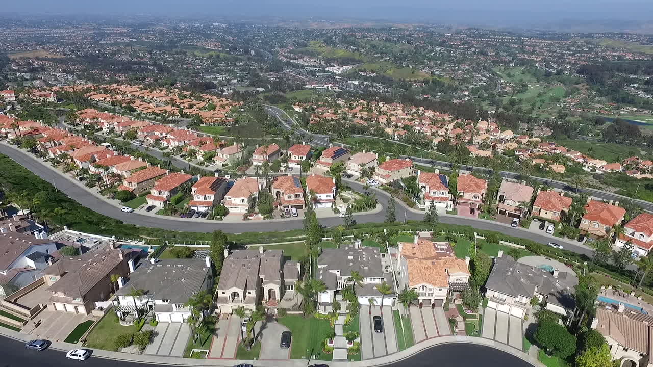 Slow aerial drone flyover of luxury homes in Laguna Niguel, Orange County, California that face Aliso Creek