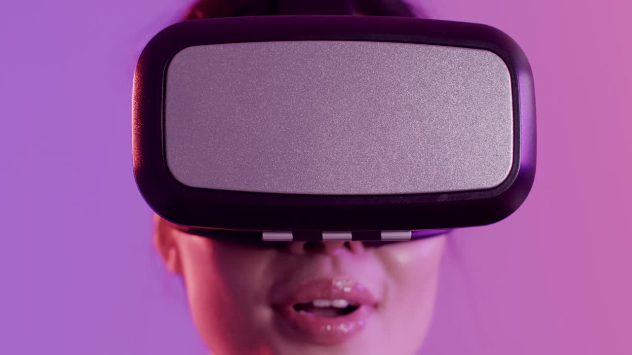 primer plano de una mujer asiática feliz usando auriculares vr sobre un fondo púrpura, cámara lenta