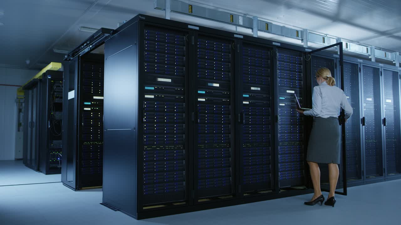 en el centro de datos: técnico informático femenino abre el gabinete de rack y ejecuta el programa de mantenimiento en la computadora portátil, controla el funcionamiento óptimo del servidor operativo.