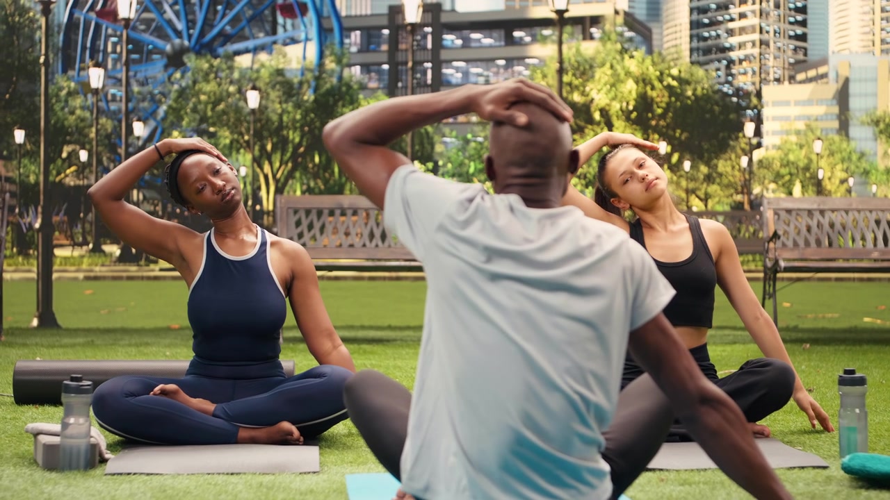 Istruttore di fronte ai partecipanti sui tappetini che piega il collo per lo stretching durante una sessione di fitness