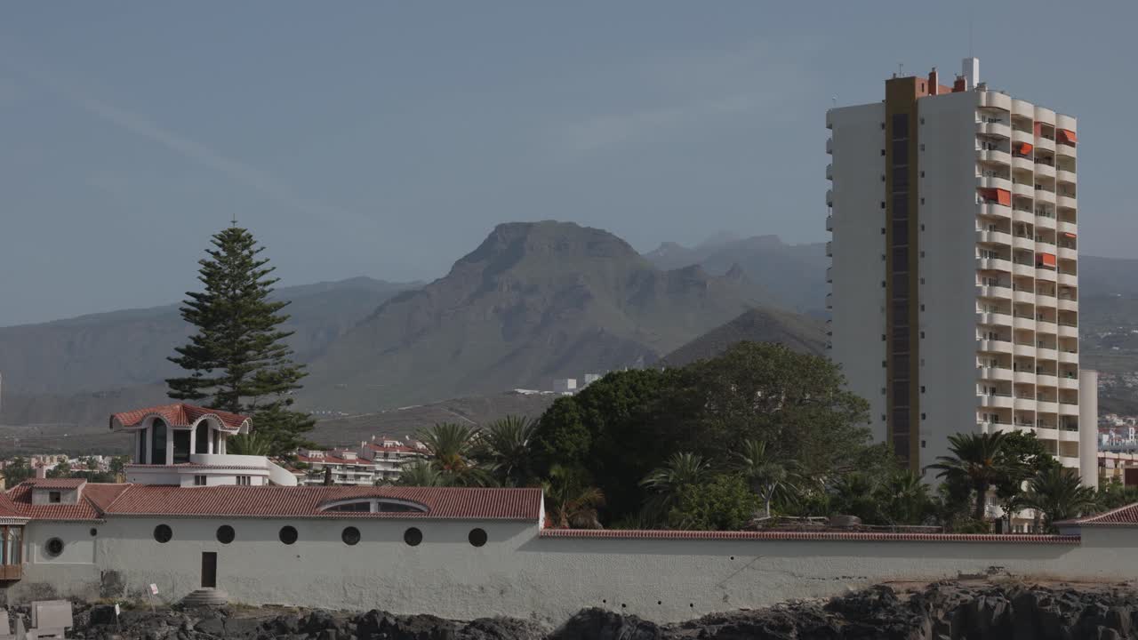 Apartment building with mountains on the background in Los Cristianos, Tenerife, Canary Islands, Spain.