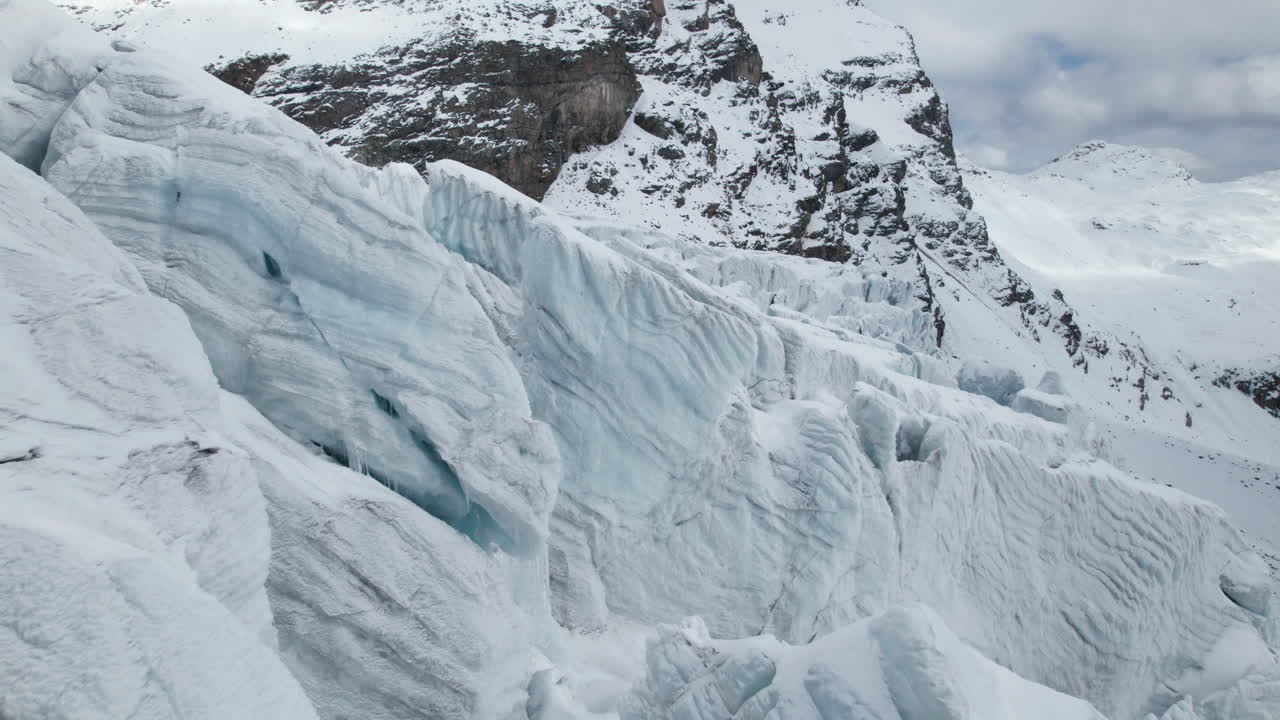 무인 항공기는 알프스에서 겨울에 화창한 날에 큰 빙하의 얼굴의 균열을 가까이서 볼 수 있습니다.