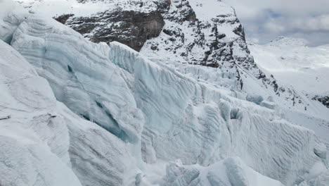 drone vista de cerca de las grietas de la cara de un gran glaciar en un día soleado en invierno en los alpes