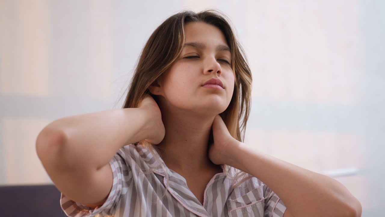 Donna allevia la tensione cervicale in modo confortevole, donna caucasica si prende una pausa ergonomica per rilassare i muscoli del collo a casa, scena interna di donna che allunga il collo per alleviare il fastidio muscolare durante il lavoro da casa
