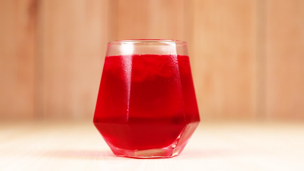 Red drink in geometric glass on wooden table