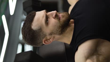 Portrait-of-muscular-athlete-works-out-in-a-modern-gym-with-dumbbells