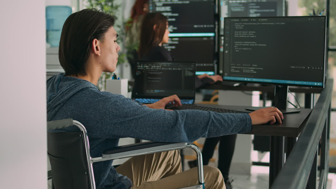Focused software developer in wheelchair writing server code in agency data room
