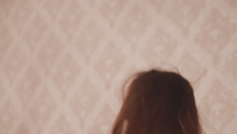 Close up of brunette girl with ombre hair in black pajamas laughing while engaged in fun pillow fight with friend, joyful expression and motion blur convey cheerful atmosphere