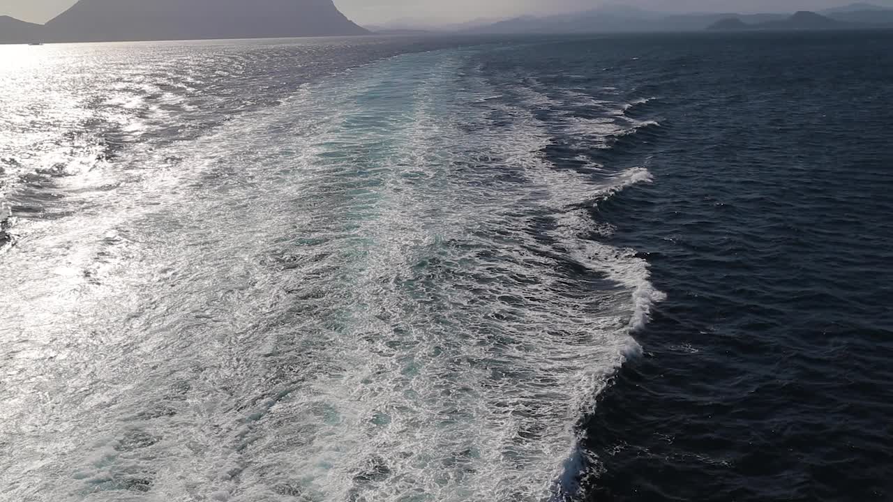 먼 산악 섬을 배경으로 바다를 위해 유람선에서 넓은 슬로우 모션 샷을 기울입니다.