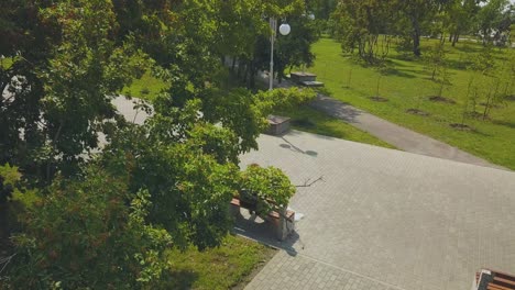 newlywed-couple-sits-on-bench-in-green-park-upper-view