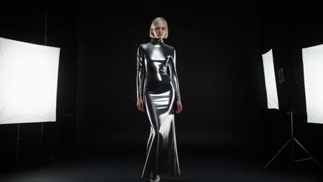 striking elegance: a model showcases futuristic fashion in a shiny metallic dress under studio lights, captivating with bold design and unique style