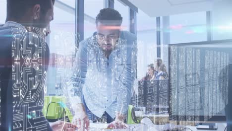 Screens-with-microprocessor-connections-against-diverse-two-male-colleagues-discussing-at-office