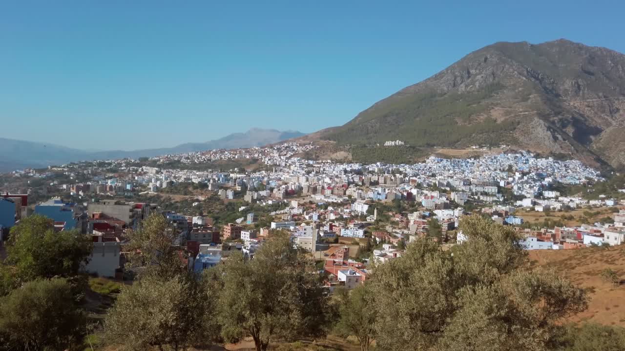 chefchaouen, la perla azul vista tradicional de la ciudad desde la distancia, rodeada por las montañas del riff en un día despejado y soleado en marruecos