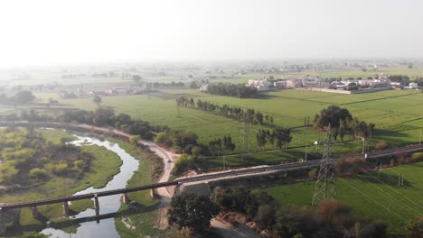 Railway-track-crossing-thought-the-green-fields-and-over-the-small-canal-and-a-road-beside-it