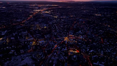 sweeping tilt reveals riga’s city grid illuminated at dusk beneath stormy clouds