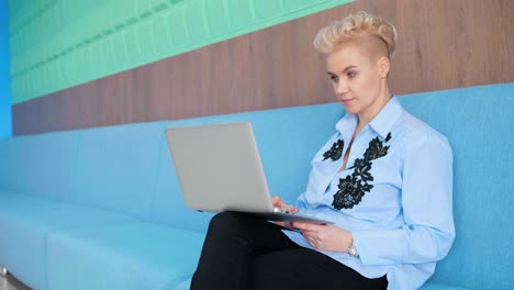 woman working on laptop on a blue sofa