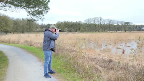 man taking videos of nature in the countryside using dslr camera