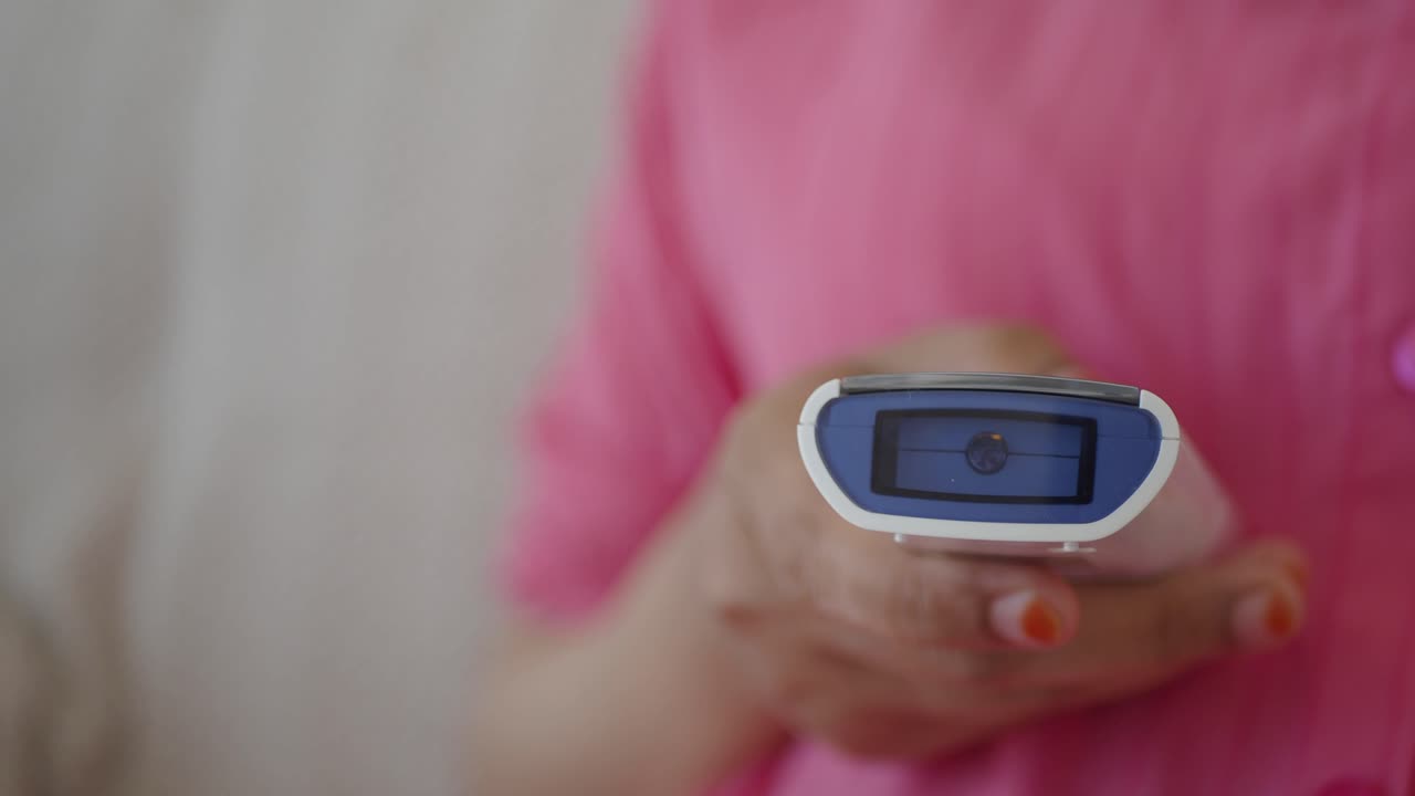 디지털 온도계를 사용하여 온도를 확인하는 여성