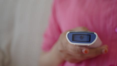 mujer usando un termómetro digital para comprobar su temperatura