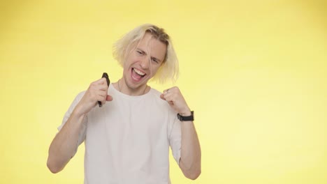 Handsome-blond-man-looking-at-his-phone-and-celebrating-online-success