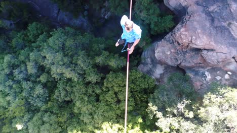 male highliner sitting on rope and balancing in countryside 4k