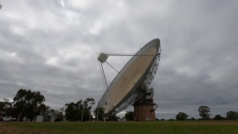 satellite dish rotates under cloudy sky over time