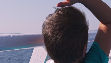 niño griego caucásico, disfrutando del viaje, en la cubierta del ferry, el fuerte viento sopla su cabello 120fps