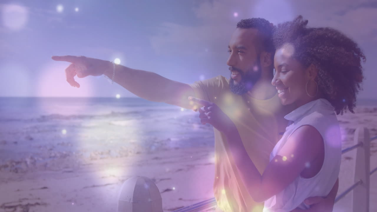Pointing at ocean, couple experiencing colorful light animation effects outdoors