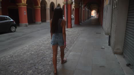 mujer caminando por una calle urbana con arcos