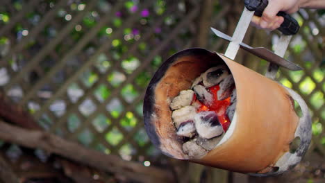 pouring hot charcoal into a grill