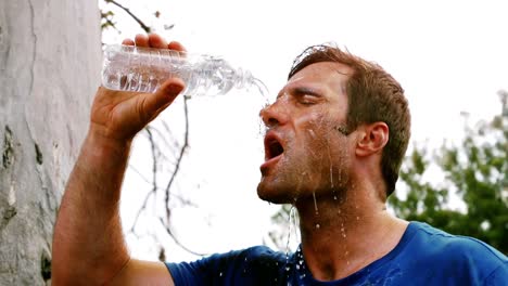 tired man pouring water on his face at boot camp