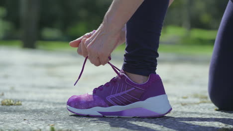 young female leg and hands tying laces on running shoe