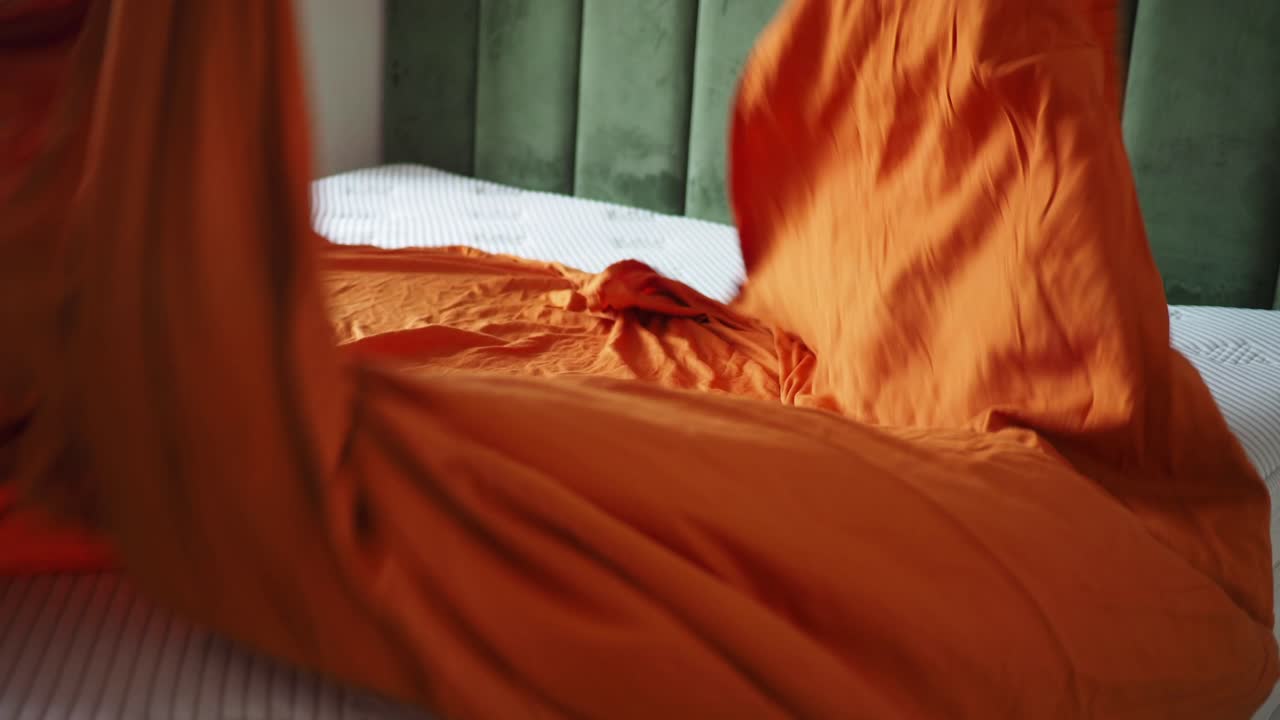 Letto con coperta arancione e cuscino
