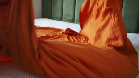 bed with orange blanket and pillow