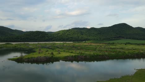 Aerial-footage-sliding-to-the-right-revealing-mountains,-a-dam-the-water-reflecting-the-sky,-Muak-Klek,-Saraburi,-Thailand