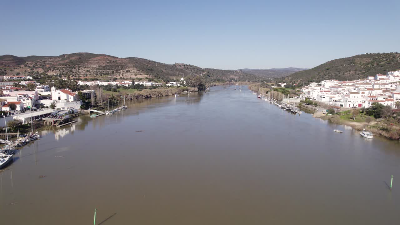 Aerial view of the Guadiana river separating Alcoutim, Portugal and Sanlucar de Guadiana, Spain, with boats moored along the banks. push forward