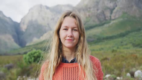 caucasian woman having a good time on a trip to the mountains, looking at camera and smiling