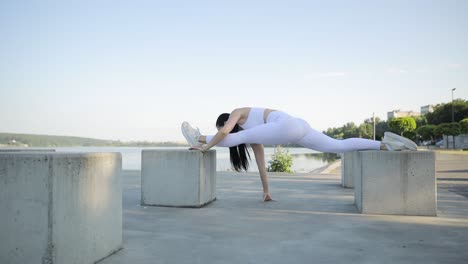 a young athlete does gymnastics on the shore of the lake sporty women do yoga on the street a young athlete does gymnastics on the shore of the lake sporty women do yoga on the street fit sportswoman doing stretching exercises outdoors
