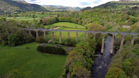 aerial view pontcysyllte aqueduct and river dee canal narrow boat bride in chirk welsh valley countryside pull away left tilt up