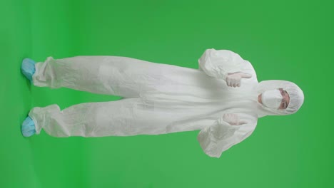 full body of asian male wearing personal protective equipment uniform ppe wearing medical face mask and showing thumbs up in green screen studio
