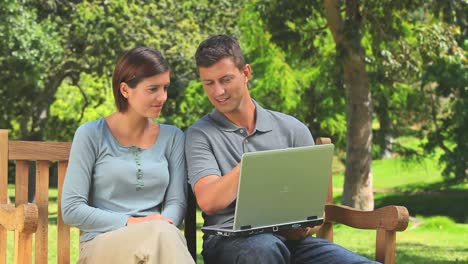 pareja joven navegando en su computadora portátil al aire libre