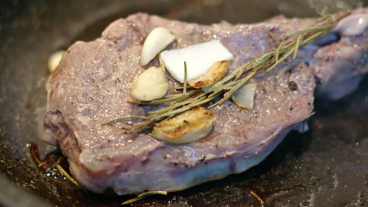 Juicy ribeye steak meat beef being prepared with rosemary and garlic